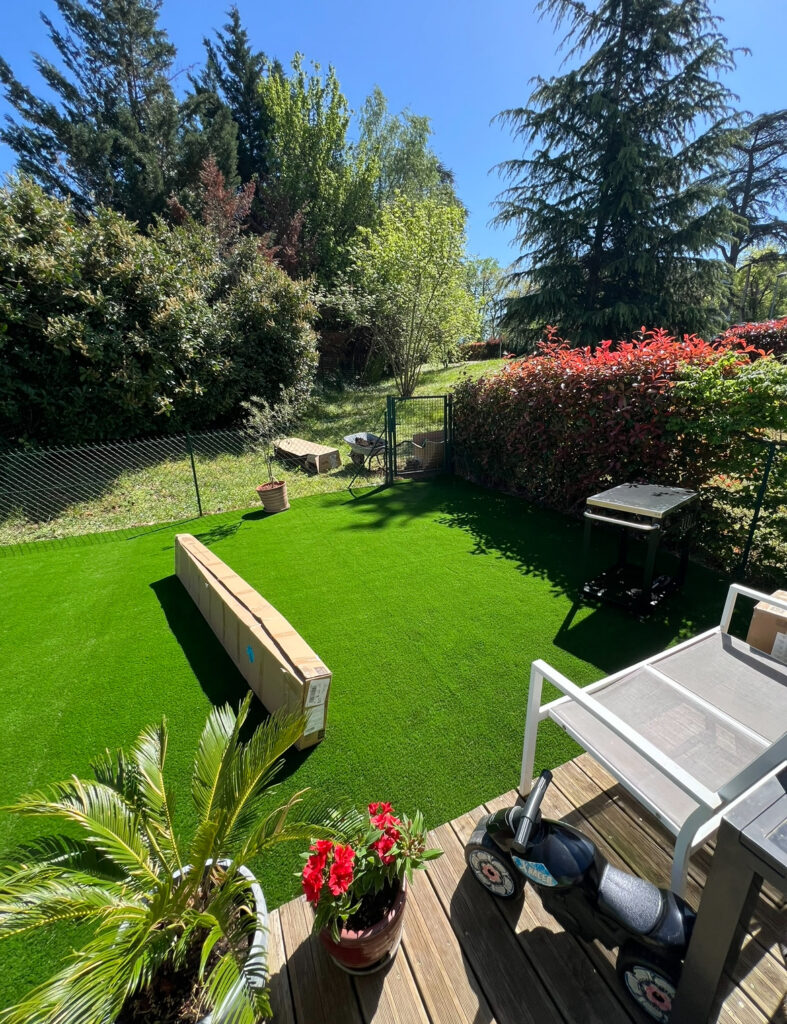 Gazon synthétique dans un jardin avec terrasse en bois